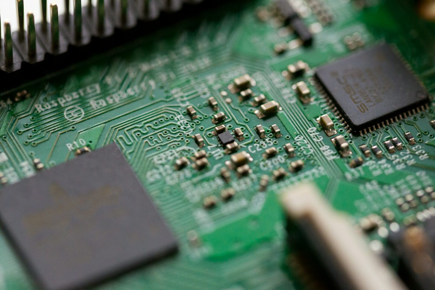 Close-up macro image of a printed circuit board and embedded chips used in firmware analysis and reverse engineering research.
